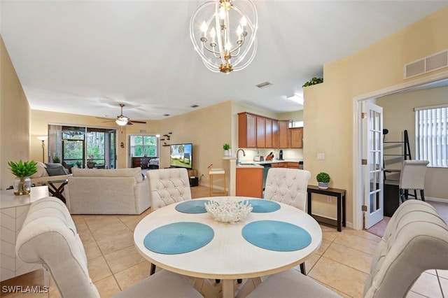 dining space with light tile patterned floors, ceiling fan with notable chandelier, visible vents, and a wealth of natural light