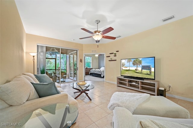 living room with light tile patterned floors, visible vents, baseboards, and a ceiling fan