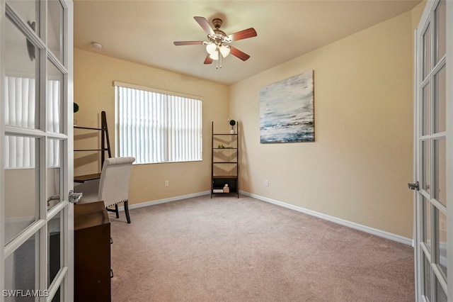 carpeted office space featuring french doors, baseboards, and ceiling fan