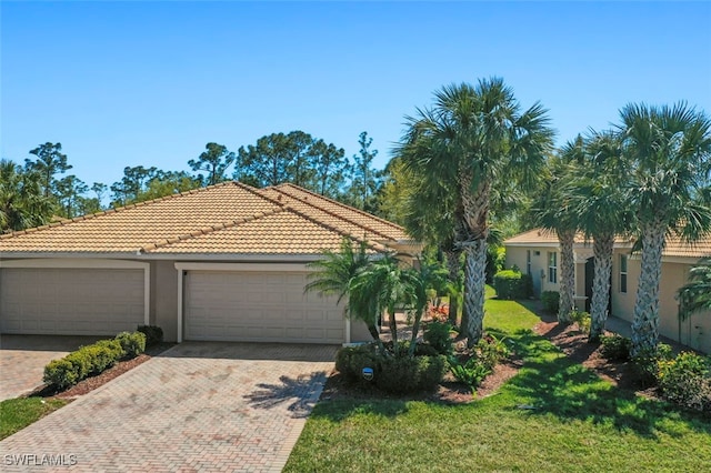 view of front of property featuring stucco siding, a garage, a front lawn, and a tiled roof