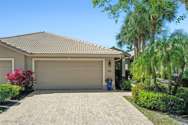 view of front facade featuring stucco siding, decorative driveway, an attached garage, and a tiled roof