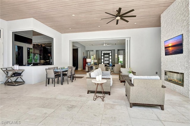 living room featuring ceiling fan, a fireplace, and wood ceiling