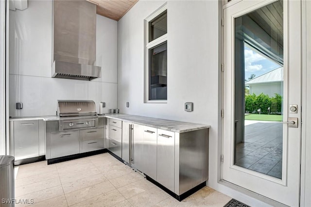 kitchen featuring gray cabinets, light tile patterned floors, and wall chimney range hood