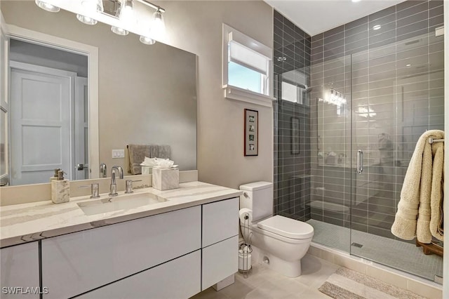 bathroom featuring a shower with door, vanity, tile patterned floors, and toilet