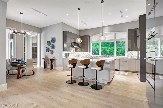 kitchen featuring tasteful backsplash, decorative light fixtures, gray cabinets, and a center island