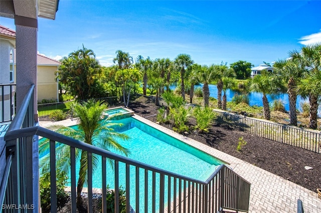 view of pool with a patio area, a water view, and an in ground hot tub