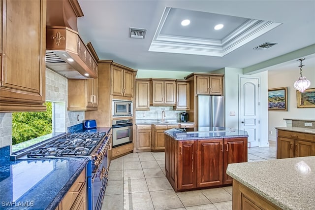 kitchen featuring tasteful backsplash, ornamental molding, appliances with stainless steel finishes, a kitchen island, and dark stone counters