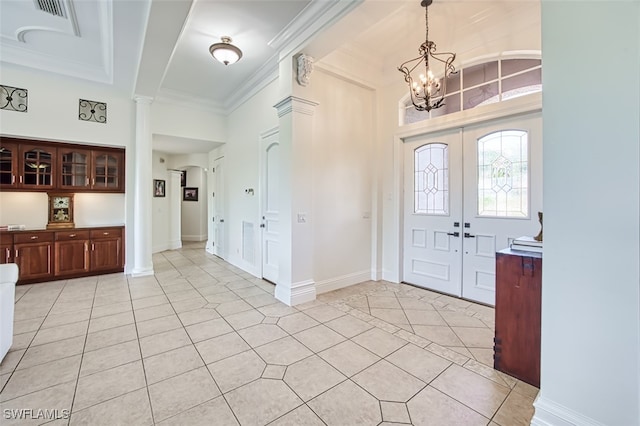 entryway featuring light tile patterned floors, decorative columns, a notable chandelier, ornamental molding, and french doors