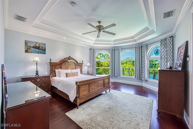 bedroom with dark hardwood / wood-style floors, ceiling fan, ornamental molding, and a tray ceiling