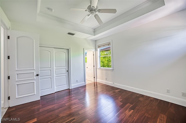 unfurnished bedroom featuring ceiling fan, dark hardwood / wood-style flooring, a raised ceiling, and a closet