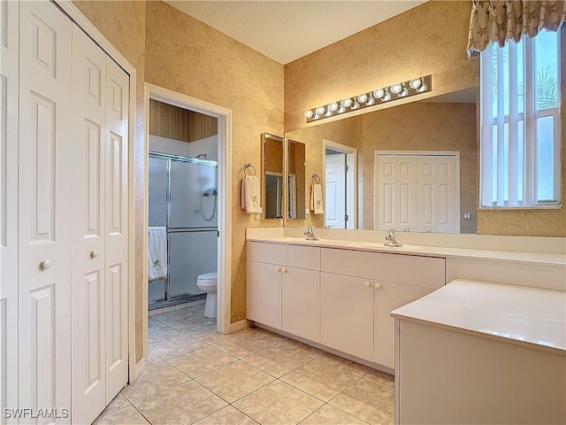 bathroom with vanity, toilet, a shower with shower door, and tile patterned flooring