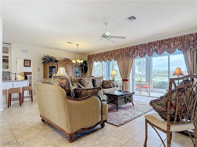 tiled living room with sink and ceiling fan with notable chandelier