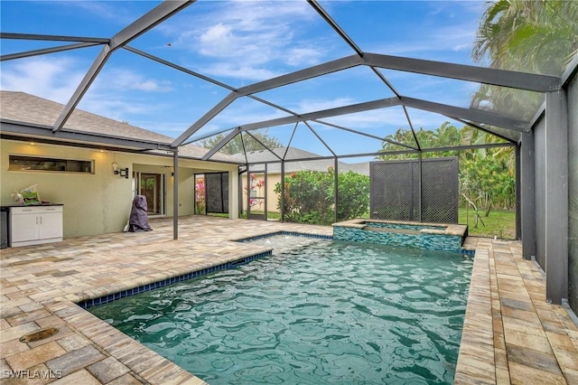 view of pool with a patio area, an in ground hot tub, and glass enclosure