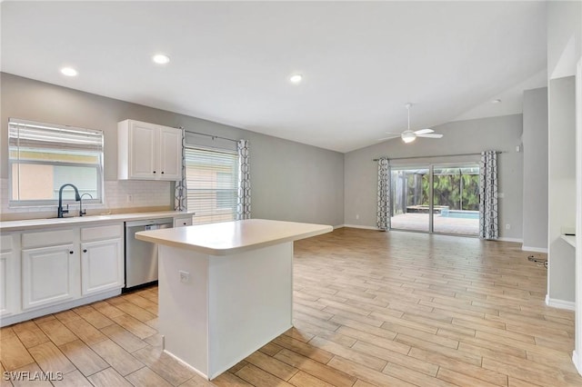 kitchen featuring vaulted ceiling, white cabinets, backsplash, a center island, and stainless steel dishwasher