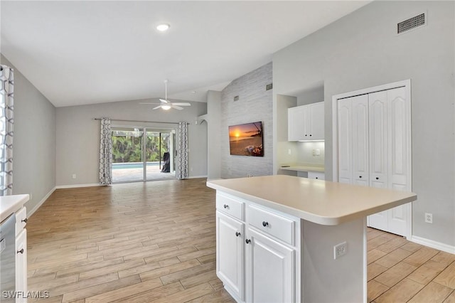 kitchen with ceiling fan, a center island, vaulted ceiling, and white cabinets