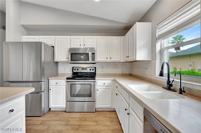 kitchen with white cabinetry, sink, vaulted ceiling, and stainless steel appliances