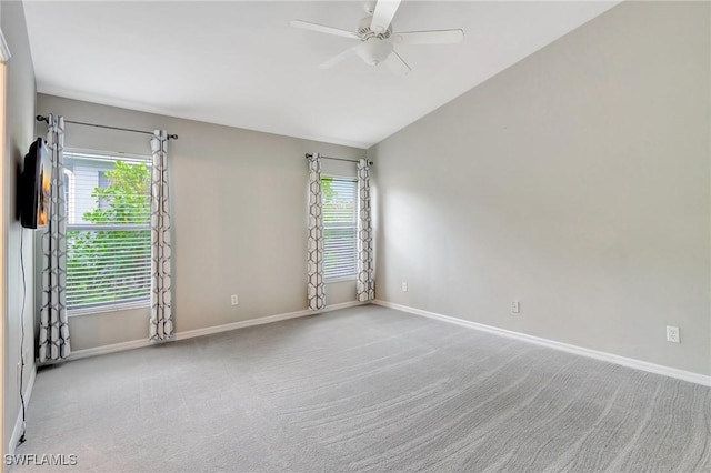 carpeted spare room featuring vaulted ceiling and ceiling fan