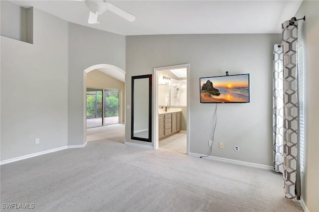 spare room featuring ceiling fan, light colored carpet, and vaulted ceiling