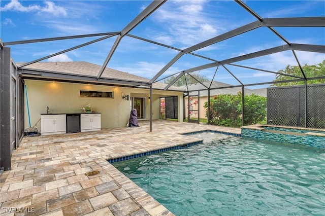 view of swimming pool with an in ground hot tub, glass enclosure, and a patio