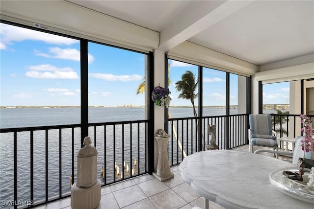 sunroom / solarium featuring beamed ceiling and a water view