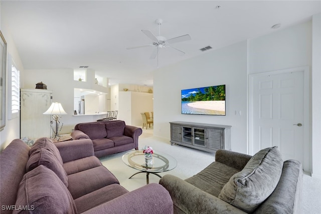 living area featuring a ceiling fan, visible vents, vaulted ceiling, and light carpet