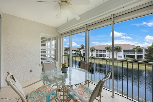 sunroom with a residential view, a water view, and ceiling fan