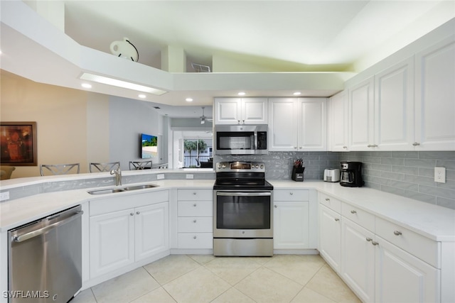 kitchen featuring white cabinetry, stainless steel appliances, a sink, and light countertops