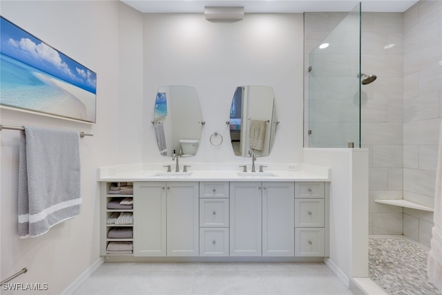 bathroom with double vanity, walk in shower, a sink, and baseboards