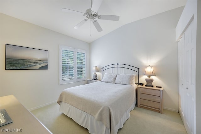 bedroom with lofted ceiling, a closet, light colored carpet, and baseboards