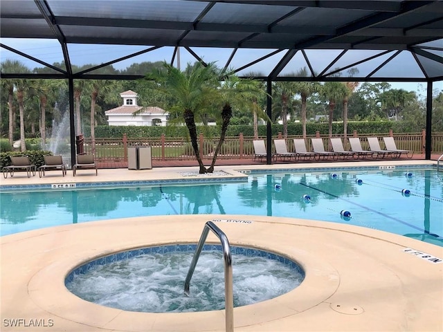 pool featuring glass enclosure, fence, and a hot tub