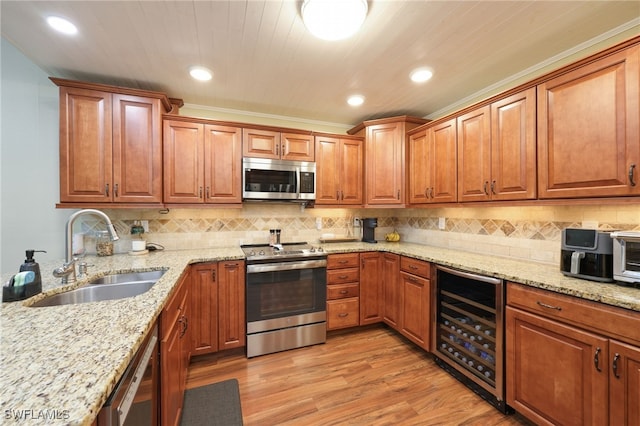 kitchen with sink, appliances with stainless steel finishes, light stone counters, beverage cooler, and light wood-type flooring