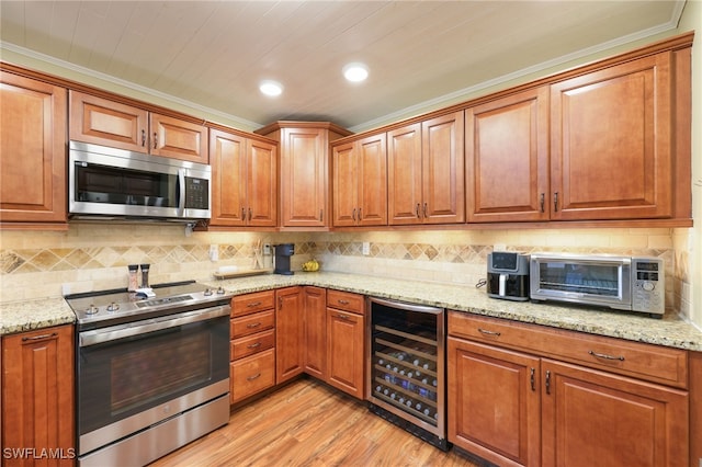 kitchen featuring stainless steel appliances, beverage cooler, light stone counters, and light hardwood / wood-style floors