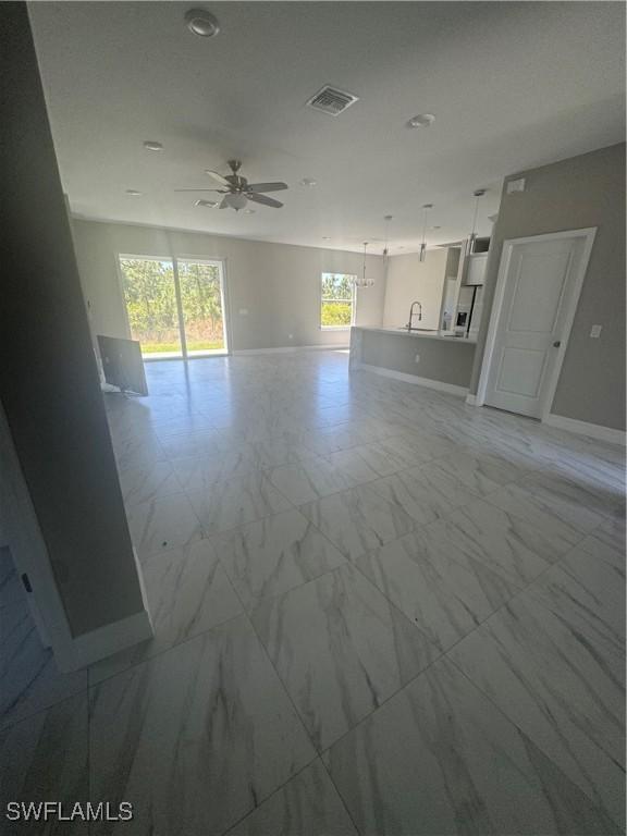 unfurnished living room featuring visible vents, marble finish floor, a ceiling fan, and baseboards