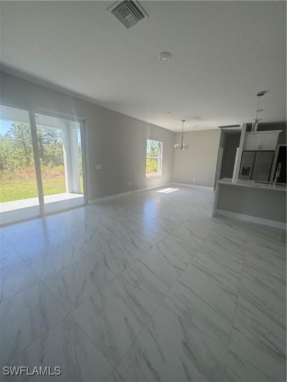 543 Mcarthur Blvd, Lehigh Acres, FL 33974 - unfurnished living room with light marble finish floors, a chandelier, and baseboards