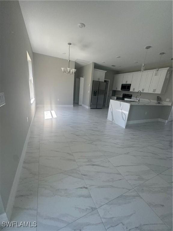 interior space featuring refrigerator, marble finish floor, white cabinetry, open floor plan, and a chandelier