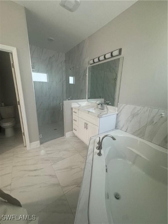 full bath featuring vanity, a shower stall, a garden tub, toilet, and marble finish floor