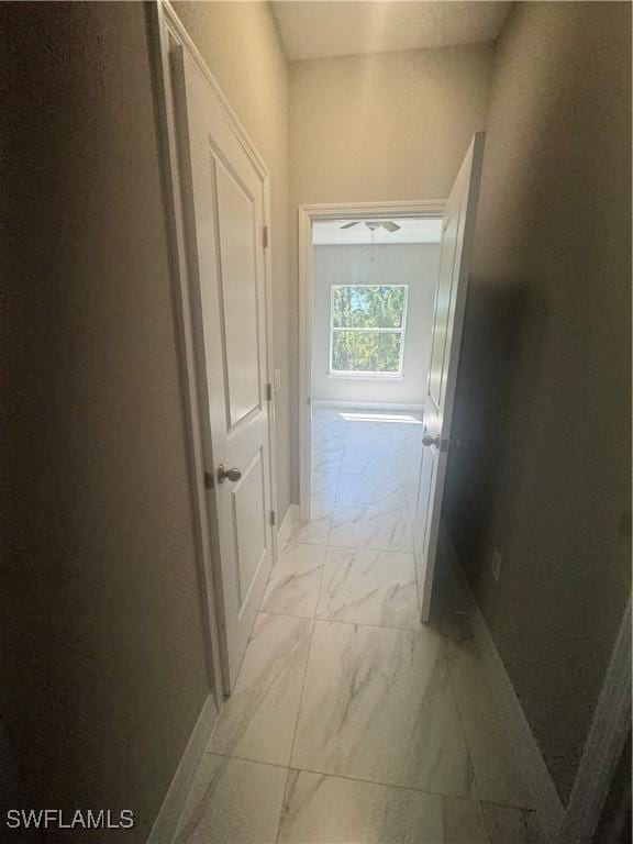 hall featuring marble finish floor and baseboards