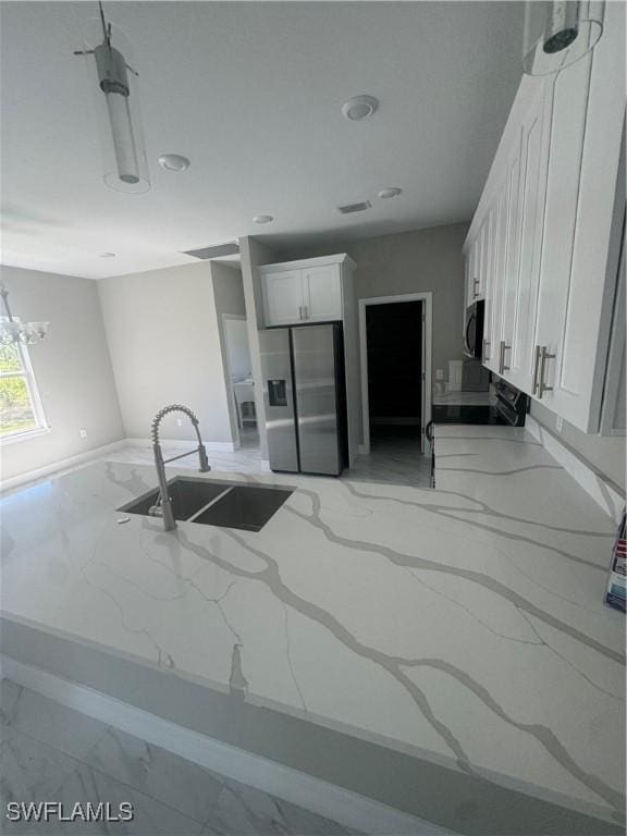 kitchen featuring light stone countertops, stainless steel fridge with ice dispenser, marble finish floor, white cabinetry, and a sink