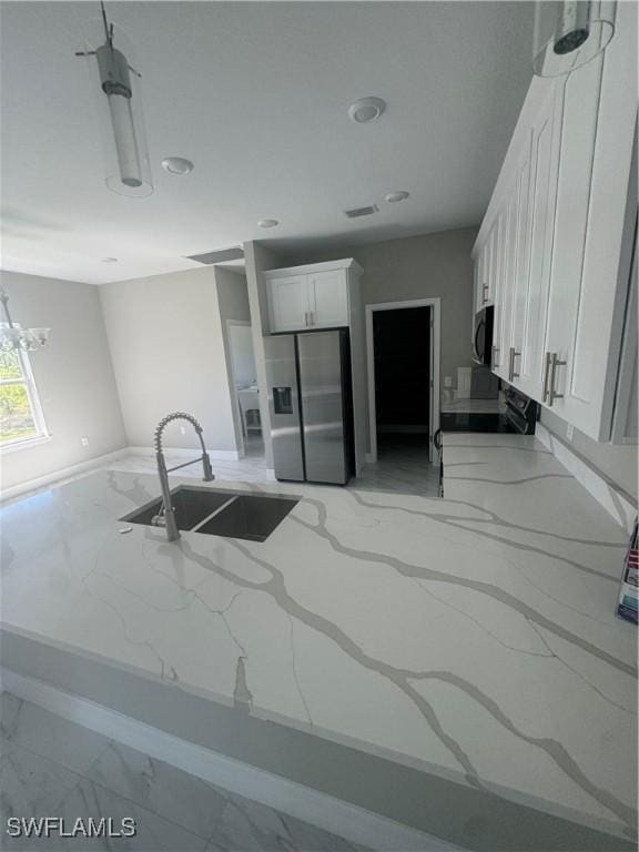 543 Mcarthur Blvd, Lehigh Acres, FL 33974 - kitchen with light marble finish floors, stainless steel appliances, a sink, light stone countertops, and baseboards