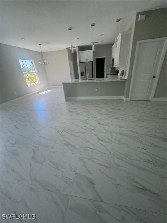 543 Mcarthur Blvd, Lehigh Acres, FL 33974 - unfurnished living room featuring light marble finish floors, a chandelier, baseboards, and a sink