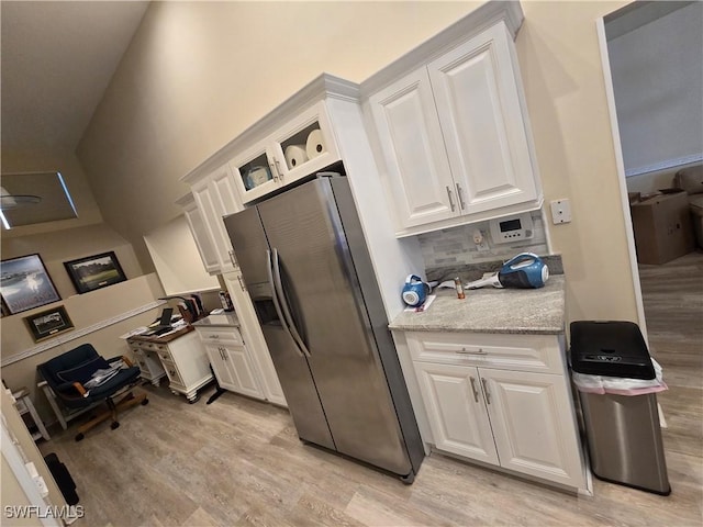 kitchen with stainless steel fridge, light wood finished floors, and white cabinetry