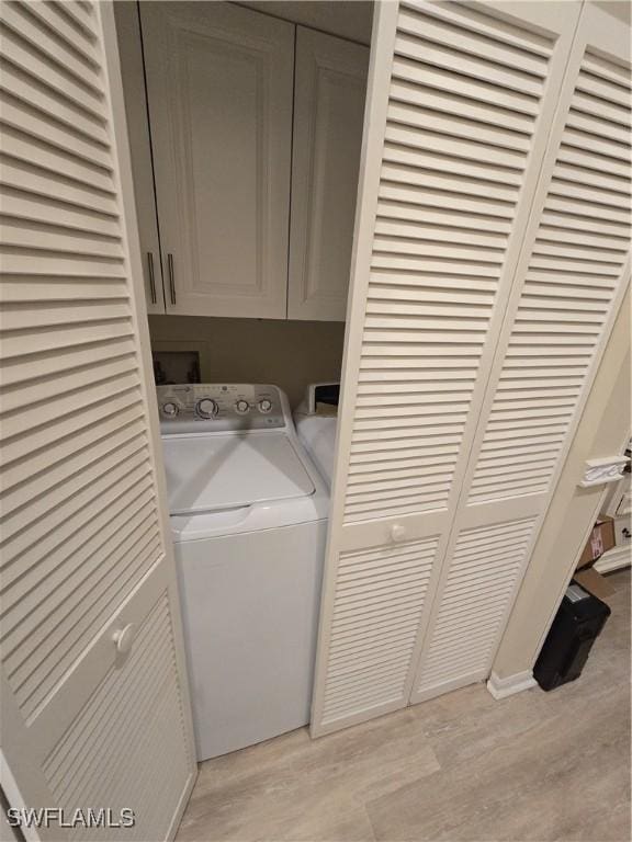 laundry area featuring washer / clothes dryer, cabinet space, and light wood-style flooring