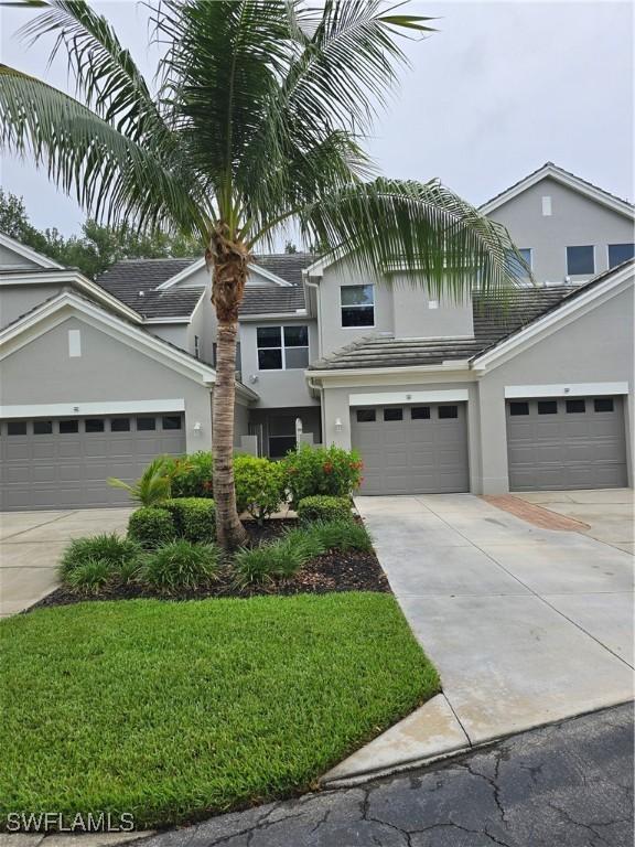 12051 Champions Green Way Unit 322, Fort Myers, FL 33913 - traditional home with stucco siding, driveway, a garage, and a front yard