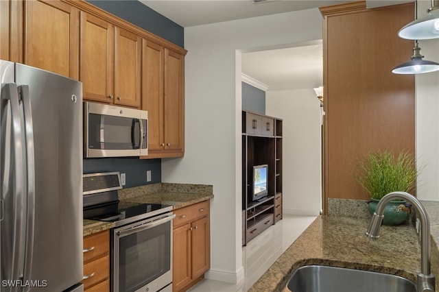 kitchen with sink, crown molding, dark stone counters, and stainless steel appliances