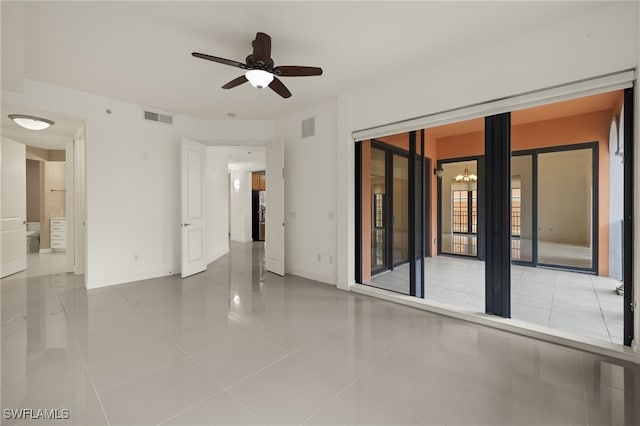 empty room featuring light tile patterned floors and ceiling fan with notable chandelier