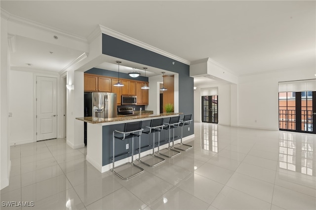 kitchen featuring kitchen peninsula, a breakfast bar, light stone counters, appliances with stainless steel finishes, and pendant lighting