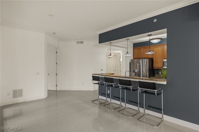 kitchen with a kitchen bar, appliances with stainless steel finishes, light tile patterned floors, pendant lighting, and ornamental molding