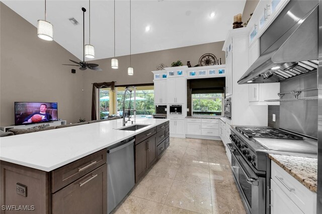 kitchen with an island with sink, wall chimney exhaust hood, white cabinets, and appliances with stainless steel finishes