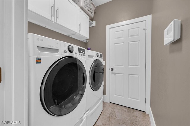 clothes washing area featuring cabinets and washer and clothes dryer