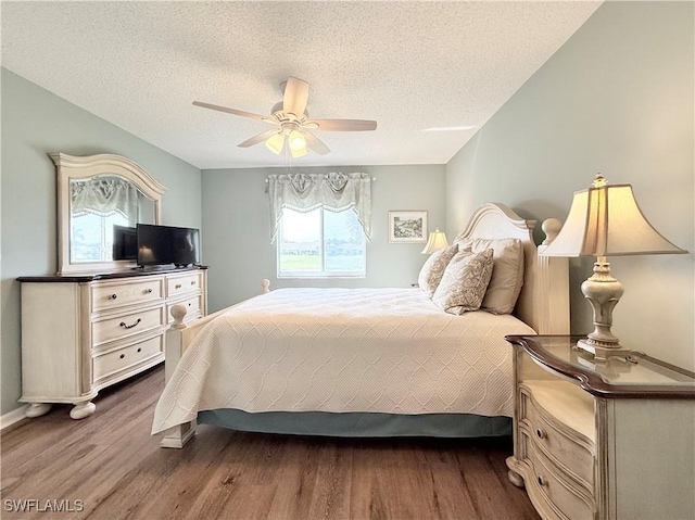 bedroom featuring ceiling fan, wood-type flooring, and a textured ceiling